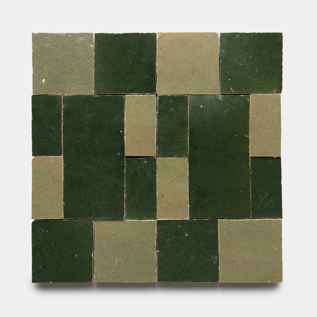 Zia Tile’s Souk 1 features a geometric, grid-like pattern of green and olive square and rectangular tiles set against a white background.