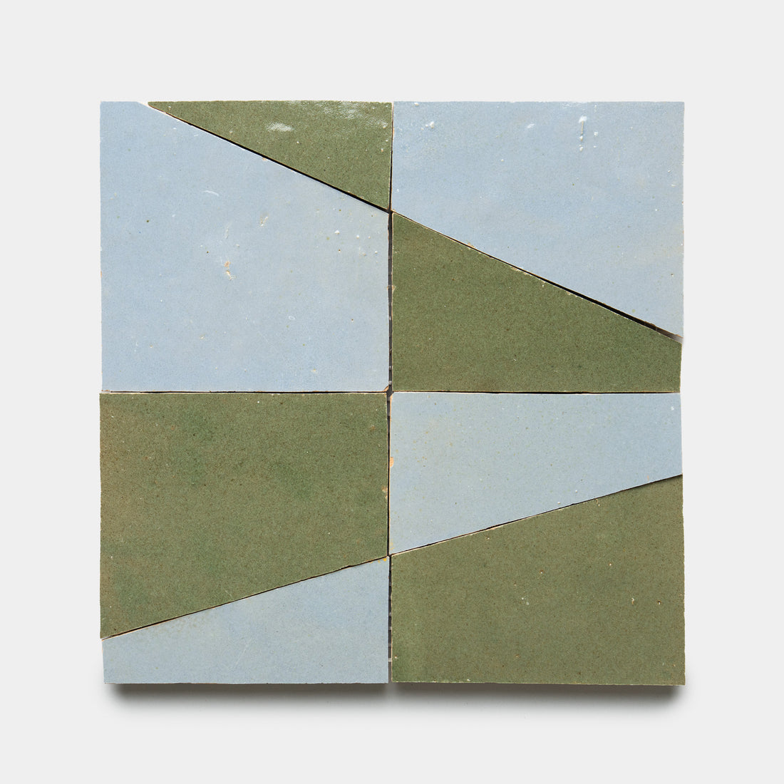 Atlas 3 by Zia Tile features four square tiles in a grid, each split diagonally into pale blue and olive green triangles. The geometric design creates intersecting lines on a plain white background.