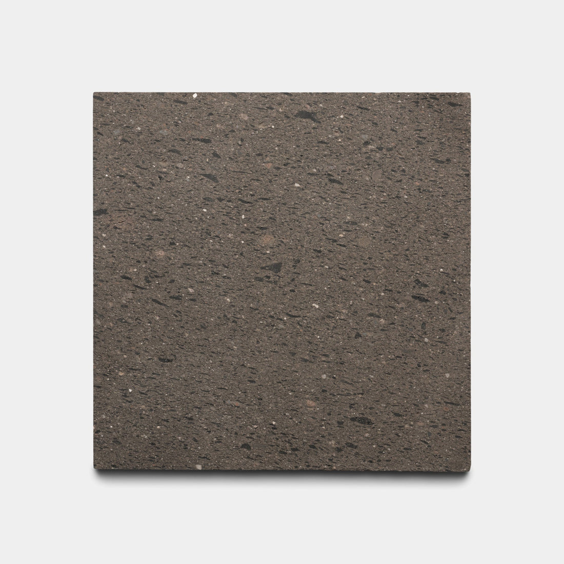 A sample of Zia Tile’s Volcan 6x6 features a square, flat stone design with a textured speckled brown surface and black and light flecks, shown on a plain white background.