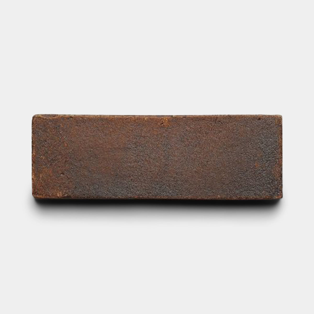 A single 2x6 Rectangle + Madera tile sample from Zia Tile, dark brown and handmade with a rough texture, is displayed against a plain white background with a faint shadow beneath it.