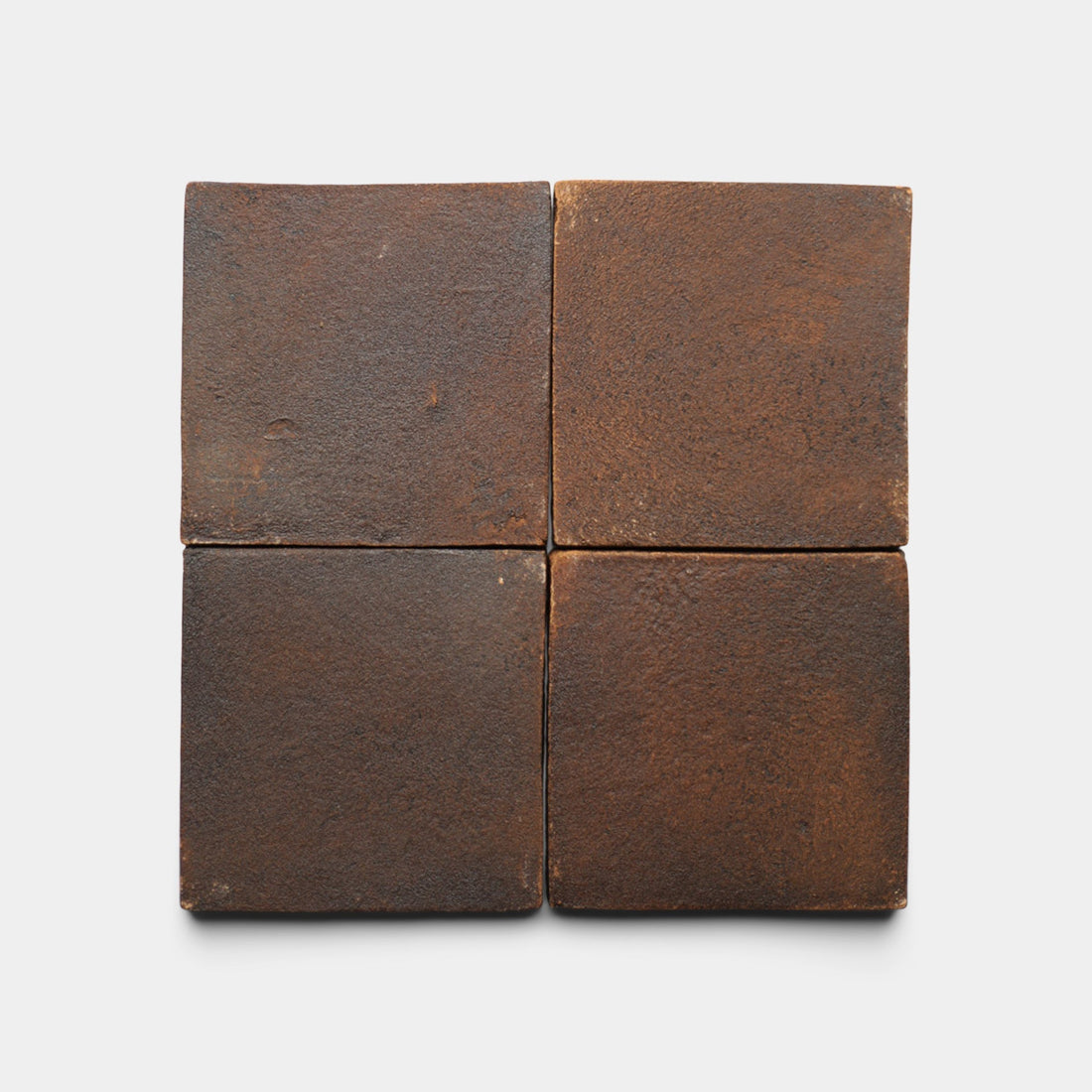 Four 4x4 Square + Madera sample tiles by Zia Tile, dark brown and handmade with a matte, slightly rough finish, are arranged in a 2x2 grid on a plain white background. The tiles show subtle variations in color and texture.