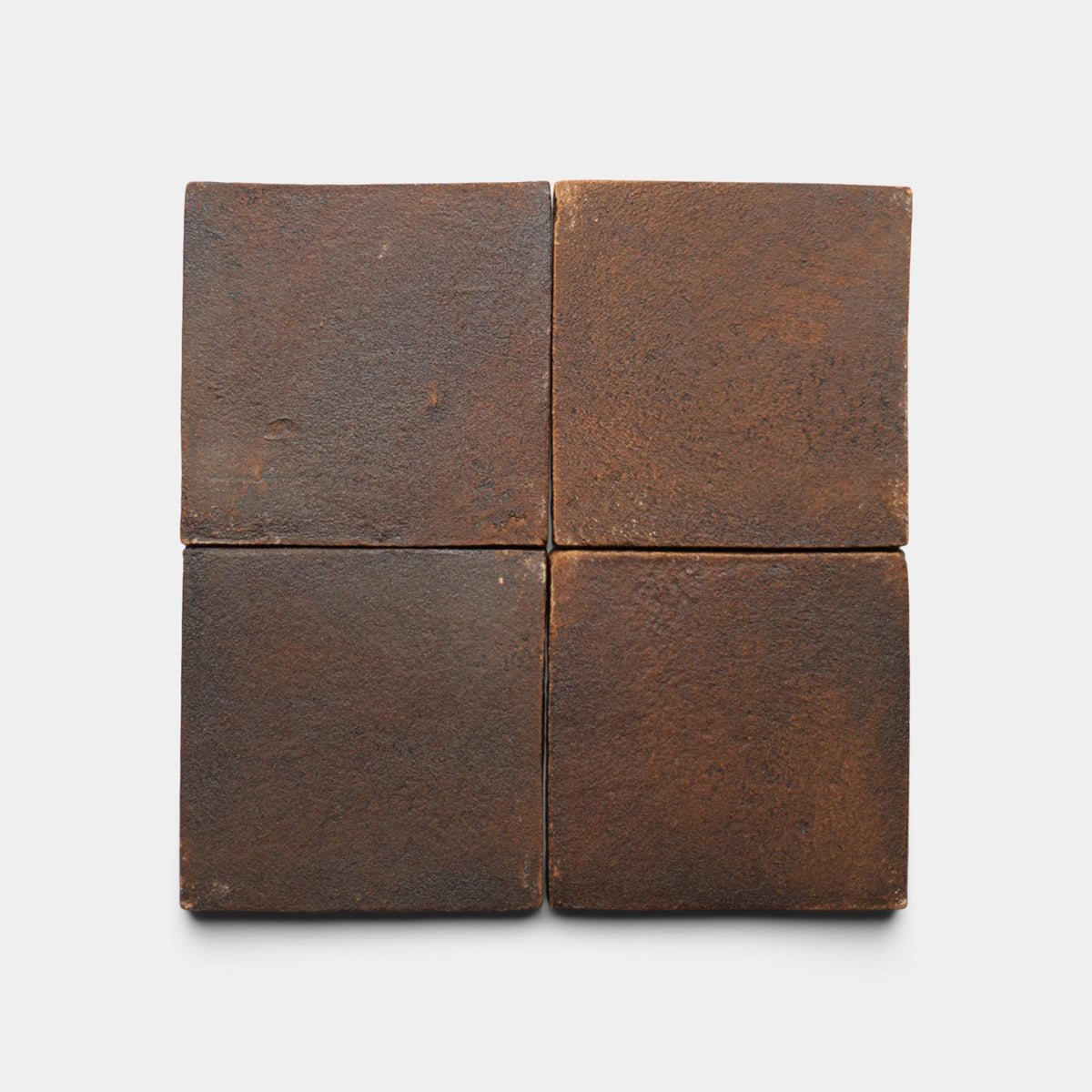 Four 4x4 Square + Madera sample tiles by Zia Tile, dark brown and handmade with a matte, slightly rough finish, are arranged in a 2x2 grid on a plain white background. The tiles show subtle variations in color and texture.