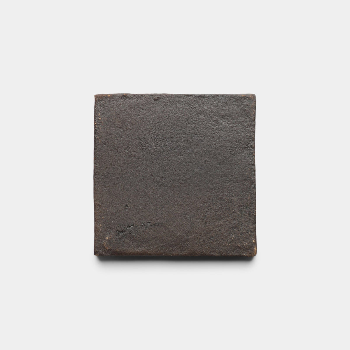A single 4x4 Square + Oscura cement tile by Zia Tile, dark brown with a rough matte texture, is centered on a plain white background.