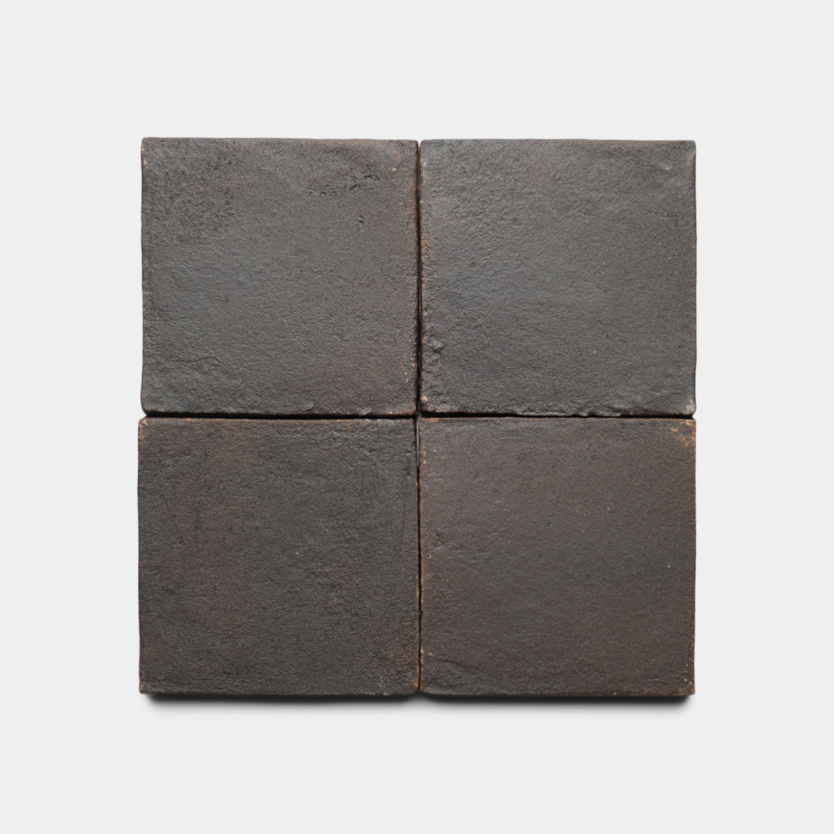 Four 4x4 Square + Oscura tiles by Zia Tile are arranged in a 2x2 grid on a light background. Their matte, rough finish and slightly uneven edges create a rustic cement tile look, highlighting the handmade character of the sample.