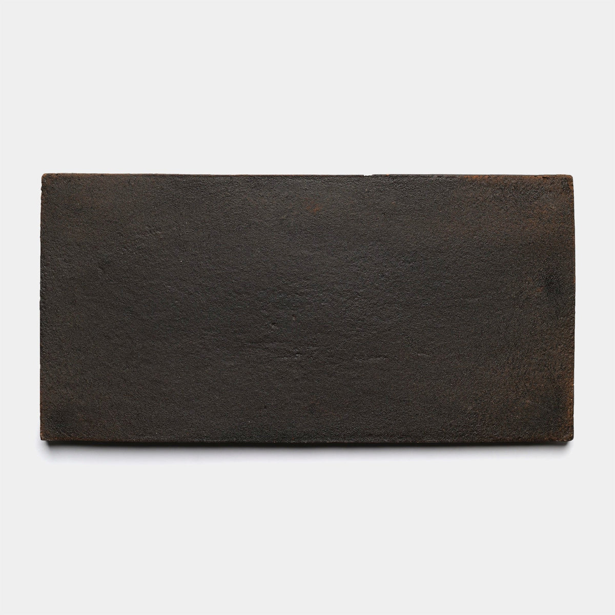 A 6.5x13-inch rectangular, flat, dark brown or black handmade tile by Zia Tile, called Rectangle + Oscura (Sample), with a rough textured surface shown on a plain white background.