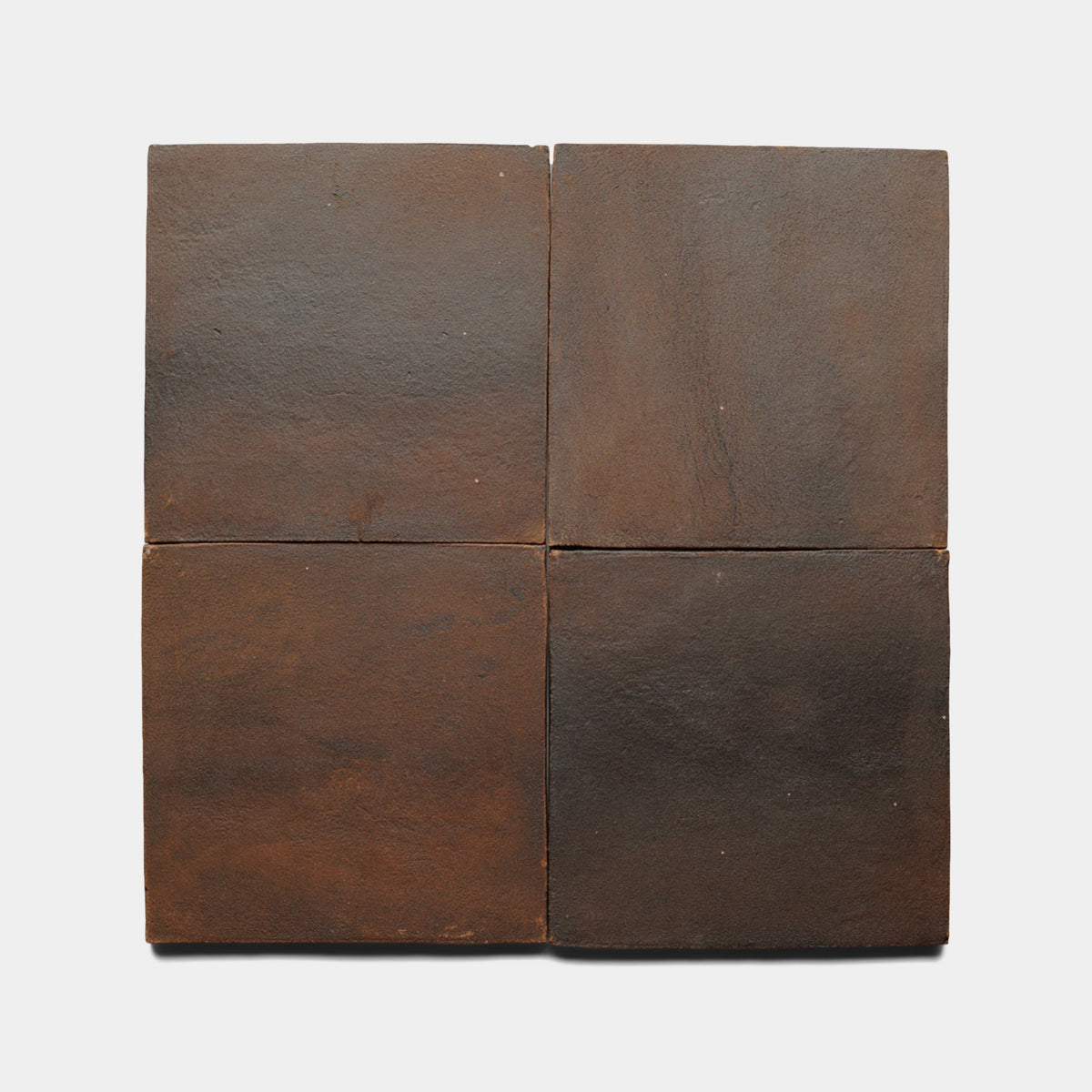 Four dark brown Zia Tile 8x8 Square + Madera samples are arranged in a two-by-two grid on a plain, light background. Each tile has a matte, slightly textured surface with subtle color variations.