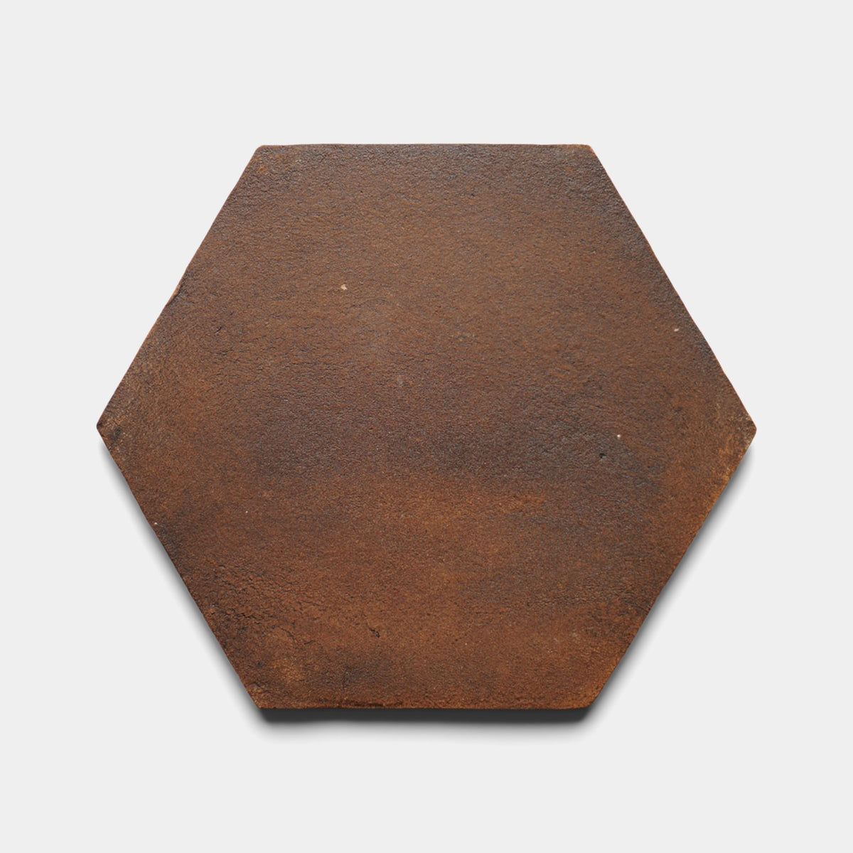The image shows the Zia Tile 8x9 Hex + Madera sample, a single flat hexagonal cement tile in a rusty brown color with a rough texture, displayed against a plain white background.