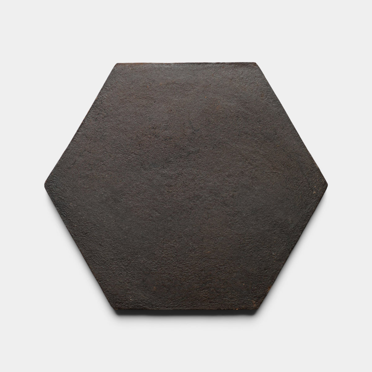 A single 8x9 Hex + Oscura tile sample by Zia Tile, dark brown with a slightly rough texture and hexagonal shape, is shown against a plain white background.
