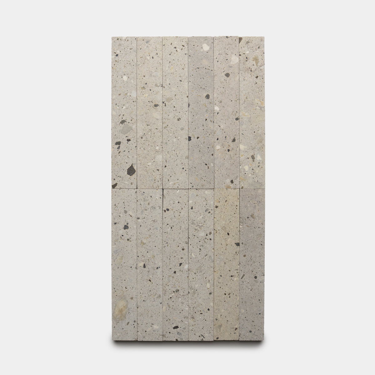 Sixteen vertically stacked Acacia 2x12 terrazzo tiles by Zia Tile, featuring light gray color with scattered darker speckles, arranged in a rectangular layout against a plain white background.