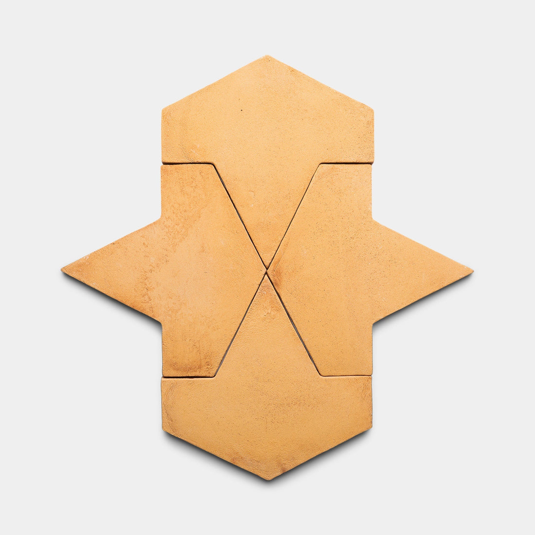 Five tan Big Alcazar + Adobe tiles by Zia Tile are arranged in a vertically stacked symmetrical pattern, forming an abstract shape with angular edges on a light gray background.