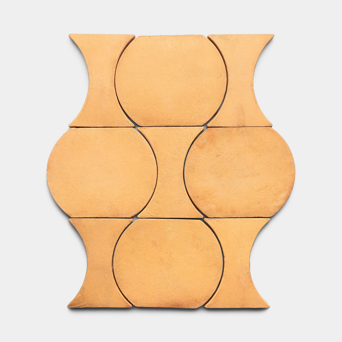 Six Oaxaca + Adobe tiles by Zia Tile form a geometric, symmetrical pattern. Each terracotta sample has a wide center and narrow curved ends, displayed against a light gray background.