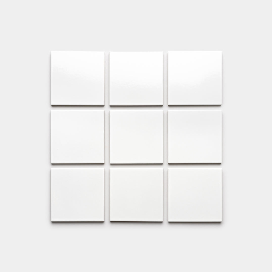 A 3x3 grid of Zia Tile’s Alabaster White 4x4 ceramic tiles on a light gray background adds an architectural grade touch.