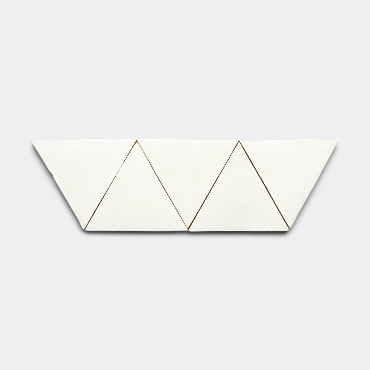 The Albar Triangle by Zia Tile features four white triangular tiles arranged in a zigzag pattern on a light gray background.