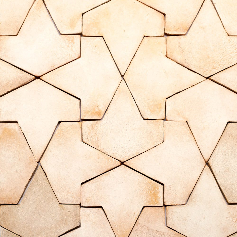 Beige ceramic tiles arranged in a geometric, interlocking star pattern with visible grout lines and subtle variations in color and texture.