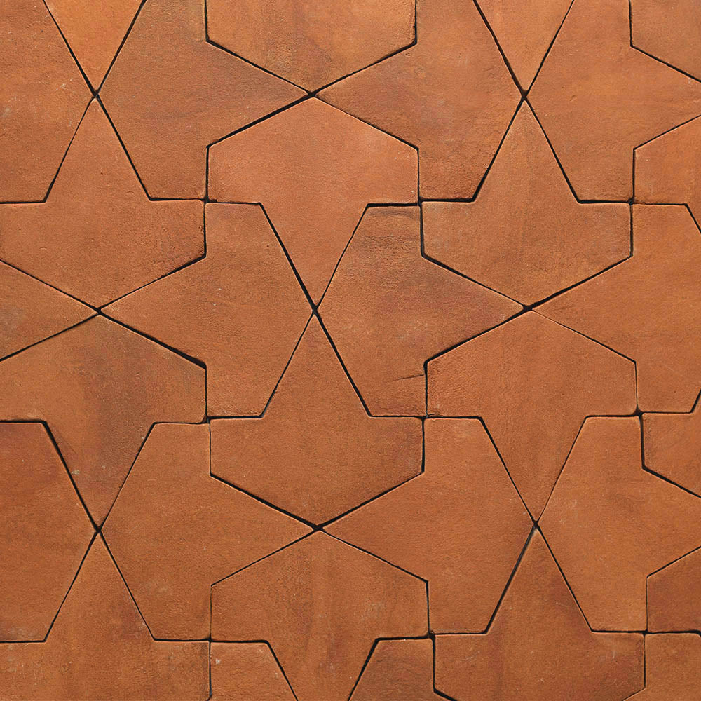 Close-up of Zia Tile's Big Alcazar + Red Clay sample, showing interlocking five-point star tiles in reddish-brown clay with a slightly rough texture, creating a geometric, repeating pattern.