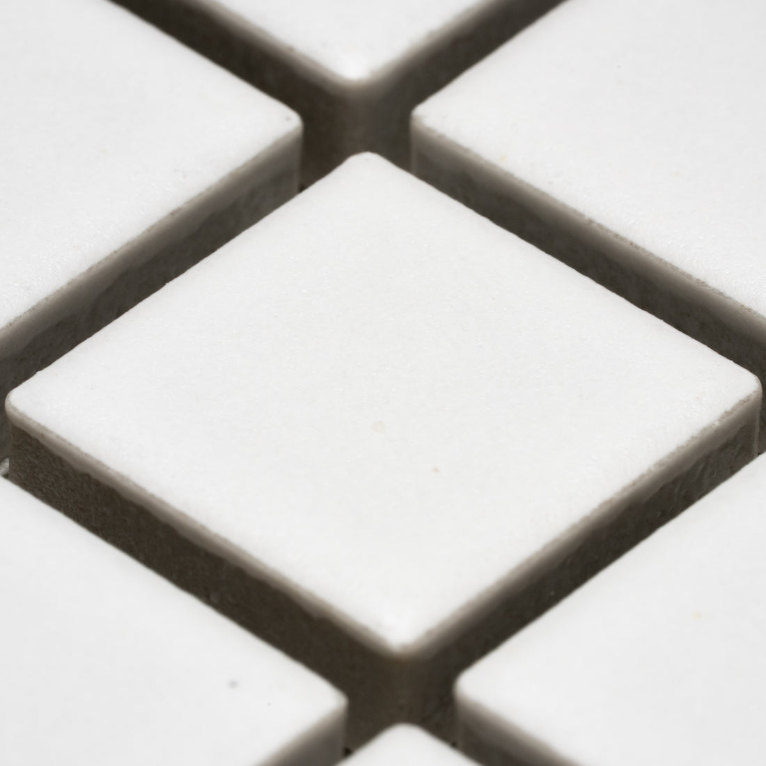 Close-up of Zia Tile’s Alpha White 1x1 tiles, arranged in a grid pattern with narrow dark grout lines separating each square.