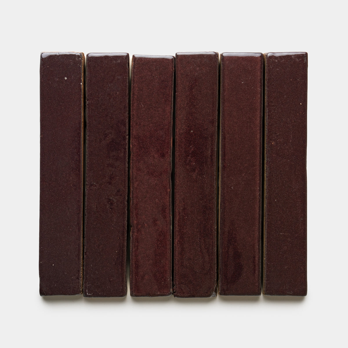 Six Ancho Mini Bar tiles by Zia Tile, each rectangular and glossy in dark red, are arranged vertically in a row against a plain white background.