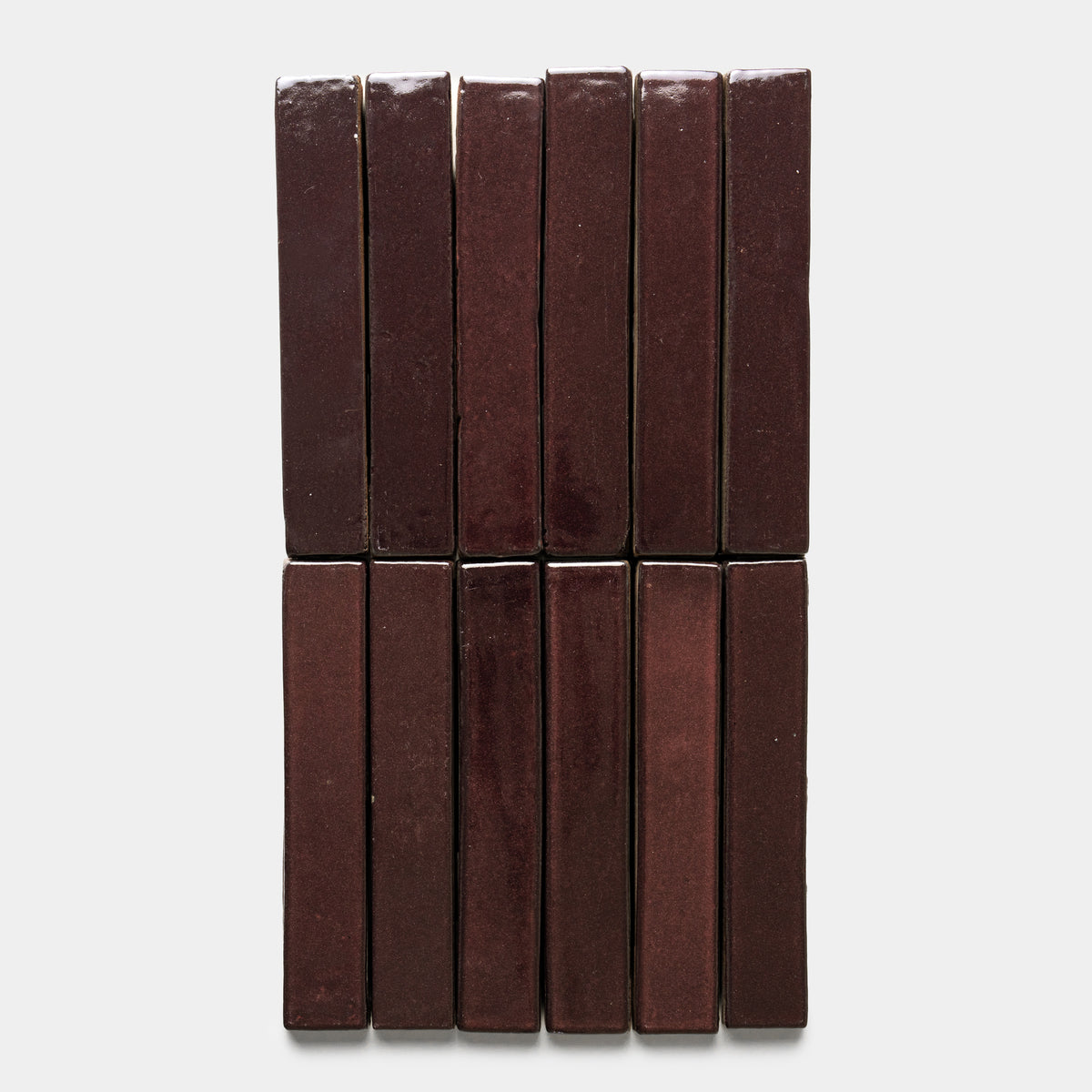 Twelve Zia Tile Ancho Mini Bar dark brown rectangular chocolate bars are arranged vertically in two neat rows on a plain white background.
