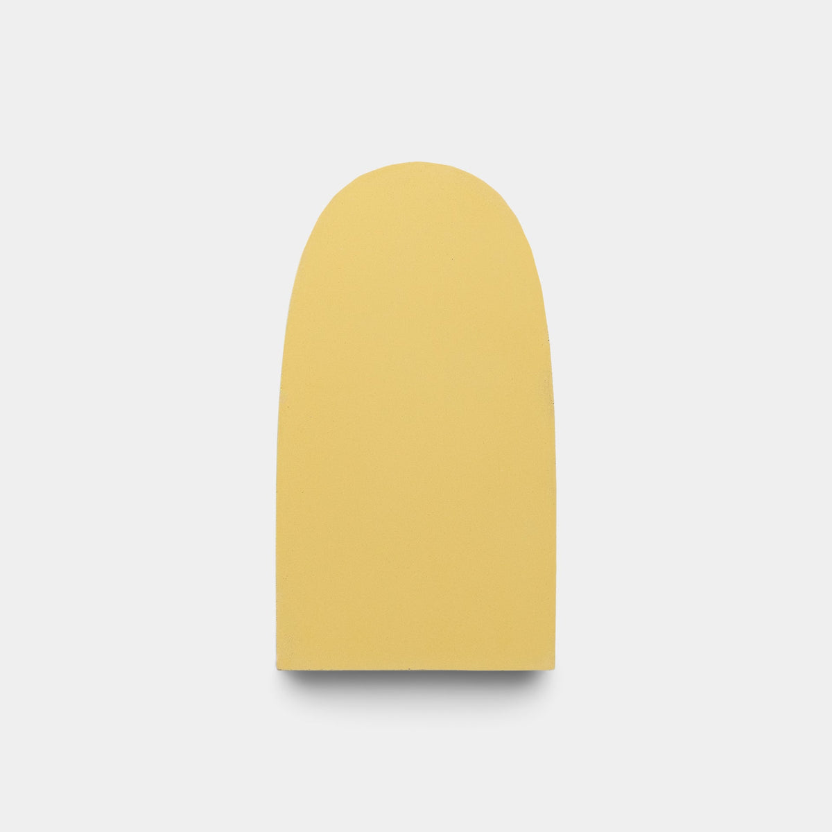 Centered on a plain white background, the Arco Bone + Black + Mustard sample by Zia Tile displays smooth curves and a flat base, evoking the look of Zia Tile’s signature handmade tiles.