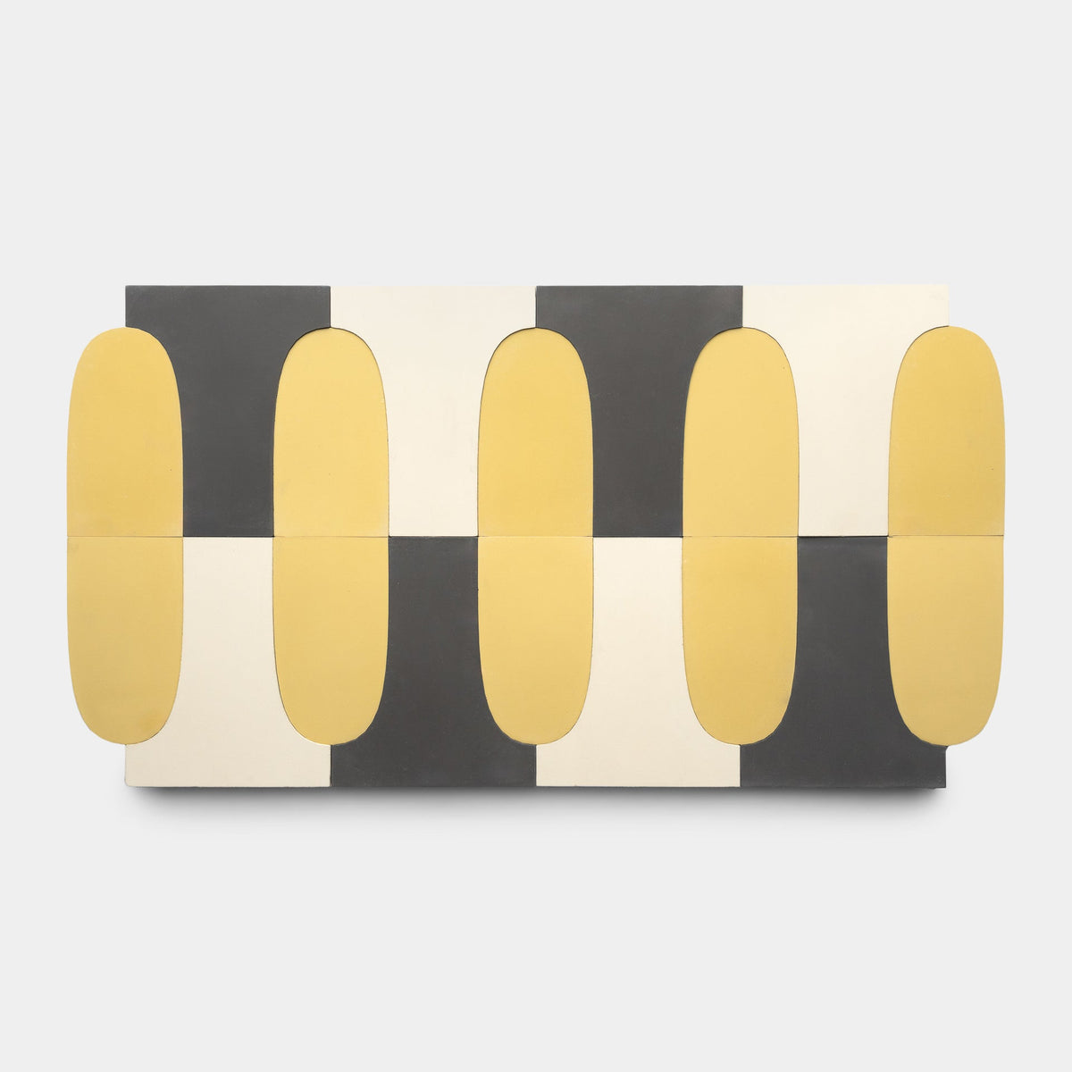 The Arco Bone + Black + Mustard sample by Zia Tile is a handmade rectangular tile featuring a geometric pattern with alternating black, white, and yellow shapes, including rounded mustard rectangles that extend past each square’s edge.