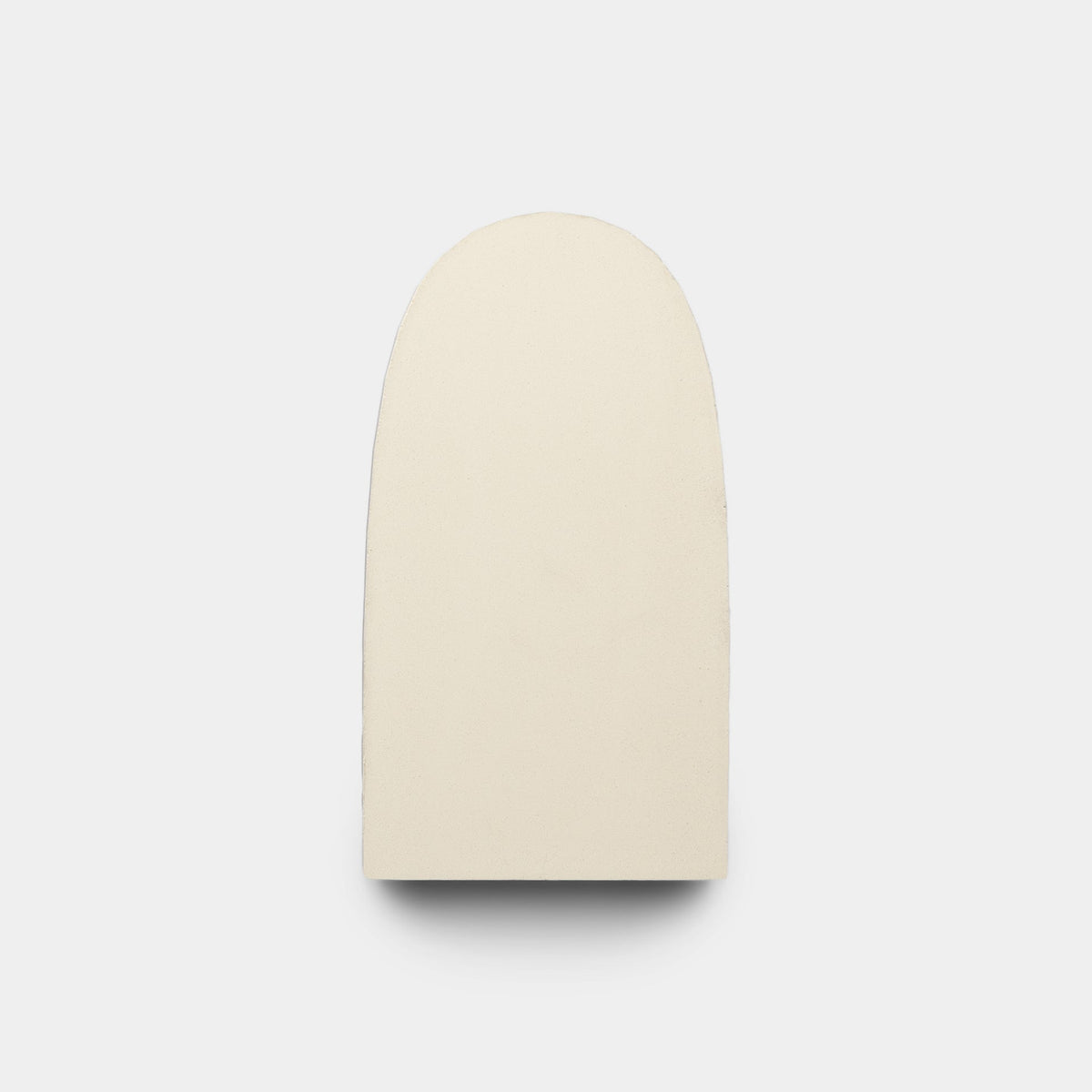 The Arco Noble Green + Bone sample by Zia Tile is a smooth, off-white, handmade rectangular tile with rounded edges and a curved top, shown on a plain white background.