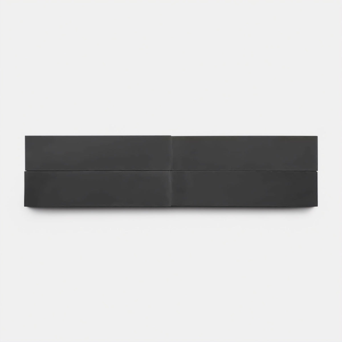 A minimalist artwork features four evenly spaced, black rectangular panels in two rows on a white background, echoing the clean lines and bold contrast of Zia Tile’s Ash 2x8, Sample.