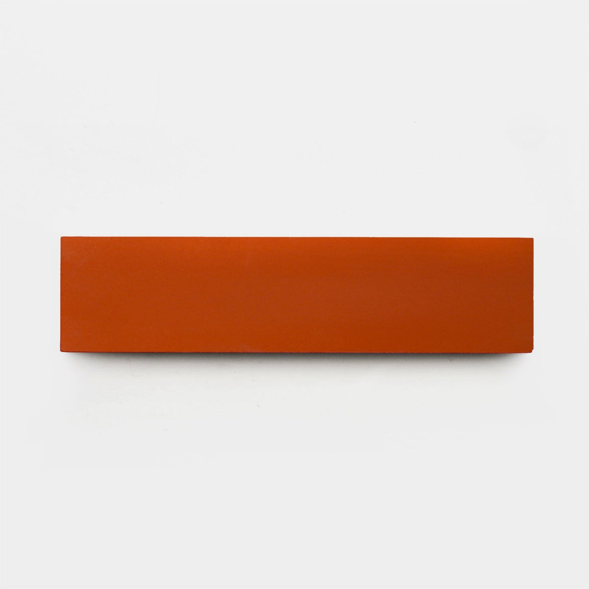 A rectangular, flat Atomic 2x8 ceramic tile sample by Zia Tile in solid red-orange is centered on a plain white background.