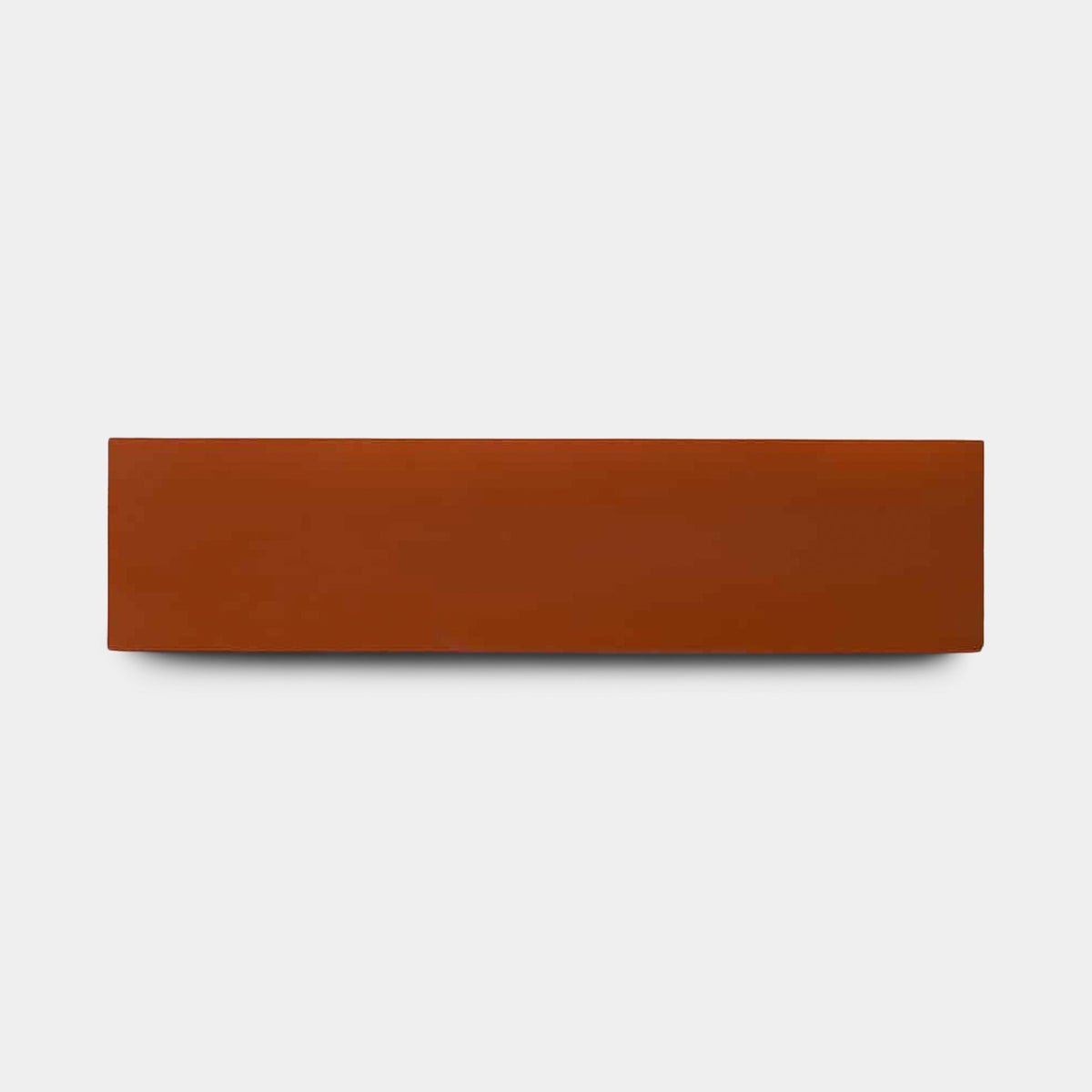 A single Atomic 2x8 sample brick by Zia Tile is centered on a plain light gray background, highlighting the timeless appeal of their ceramic tiles.