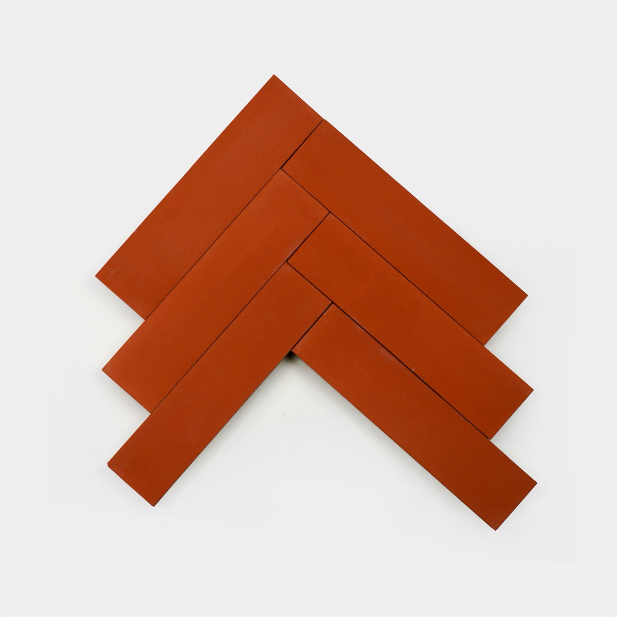 Five reddish-brown rectangular Atomic 2x8 ceramic tile samples by Zia Tile are arranged in a herringbone pattern on a plain white background.