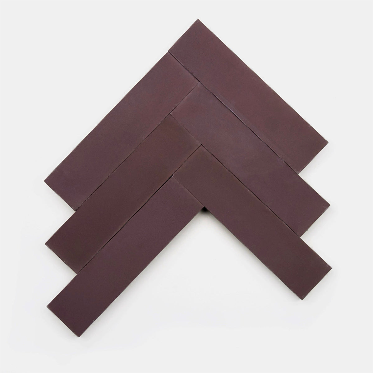 Five Zia Tile Aubergine 2x8 samples, deep brown and rectangular, are laid out in a chevron pattern on a white background to form an upward-pointing arrow.