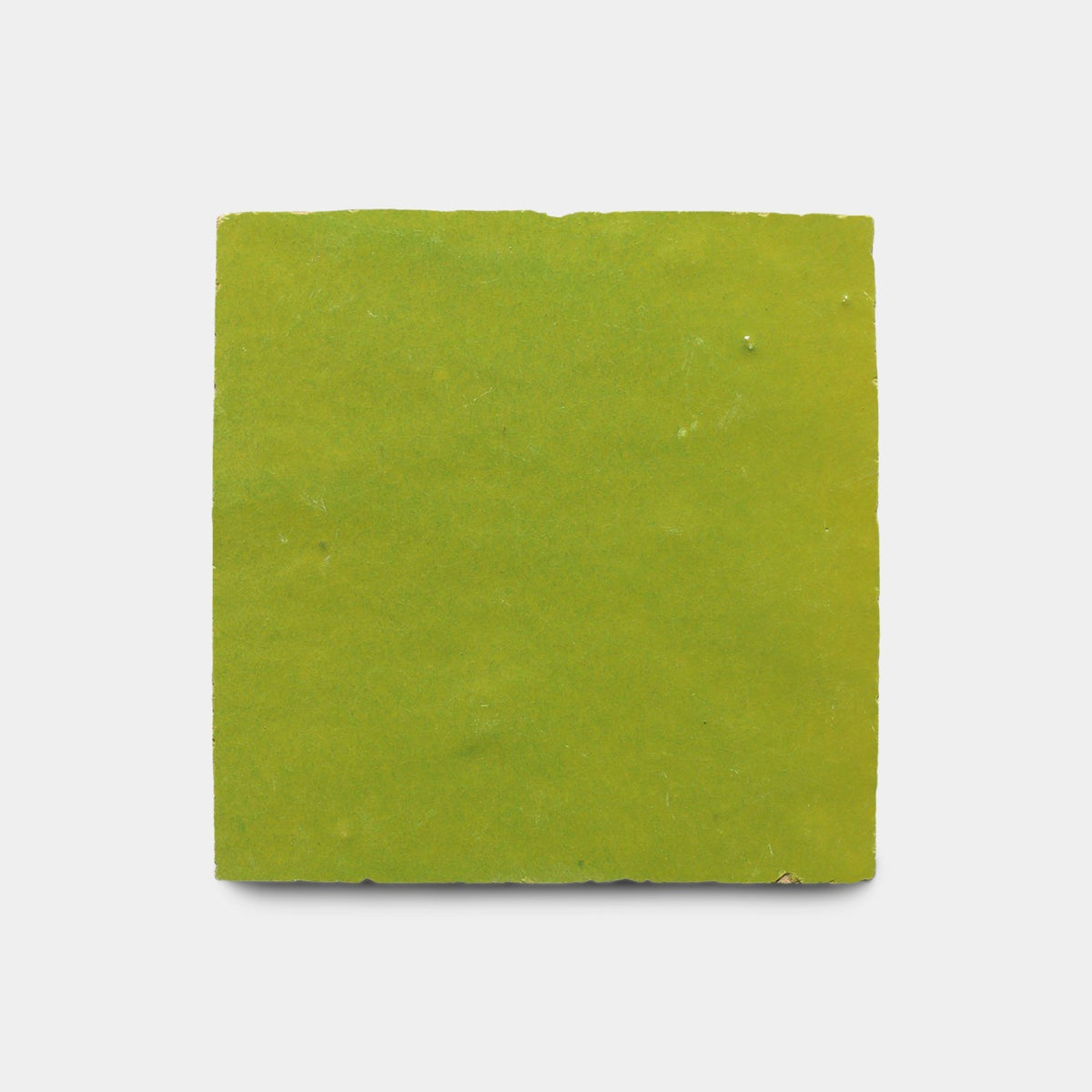 A single Avocado 4x4 sample tile by Zia Tile, square and green with a handmade touch, slightly uneven surface, and rough edges, shown on a plain white background.
