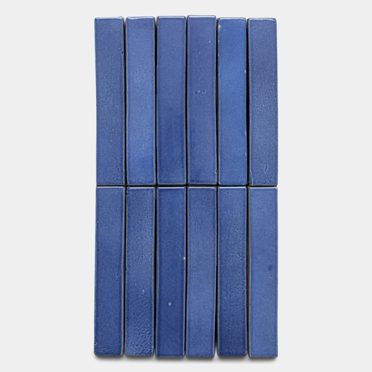 Ten Azul Mini Bar tiles by Zia Tile, featuring a rectangular blue ceramic design, are arranged in two vertical rows of five side by side on a light gray background.