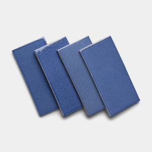 Four Azul 4x8 Rectangle tiles by Zia Tile, in blue ceramic, are arranged diagonally with slight overlap on a white background.