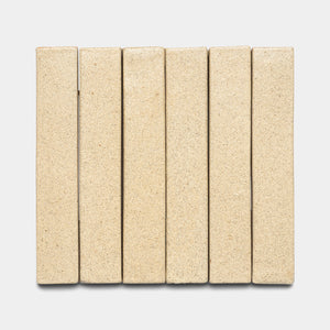 Six Zia Tile Baja Mini Bar rectangular beige bricks are arranged vertically side by side on a light gray background, forming a neat, evenly spaced row.