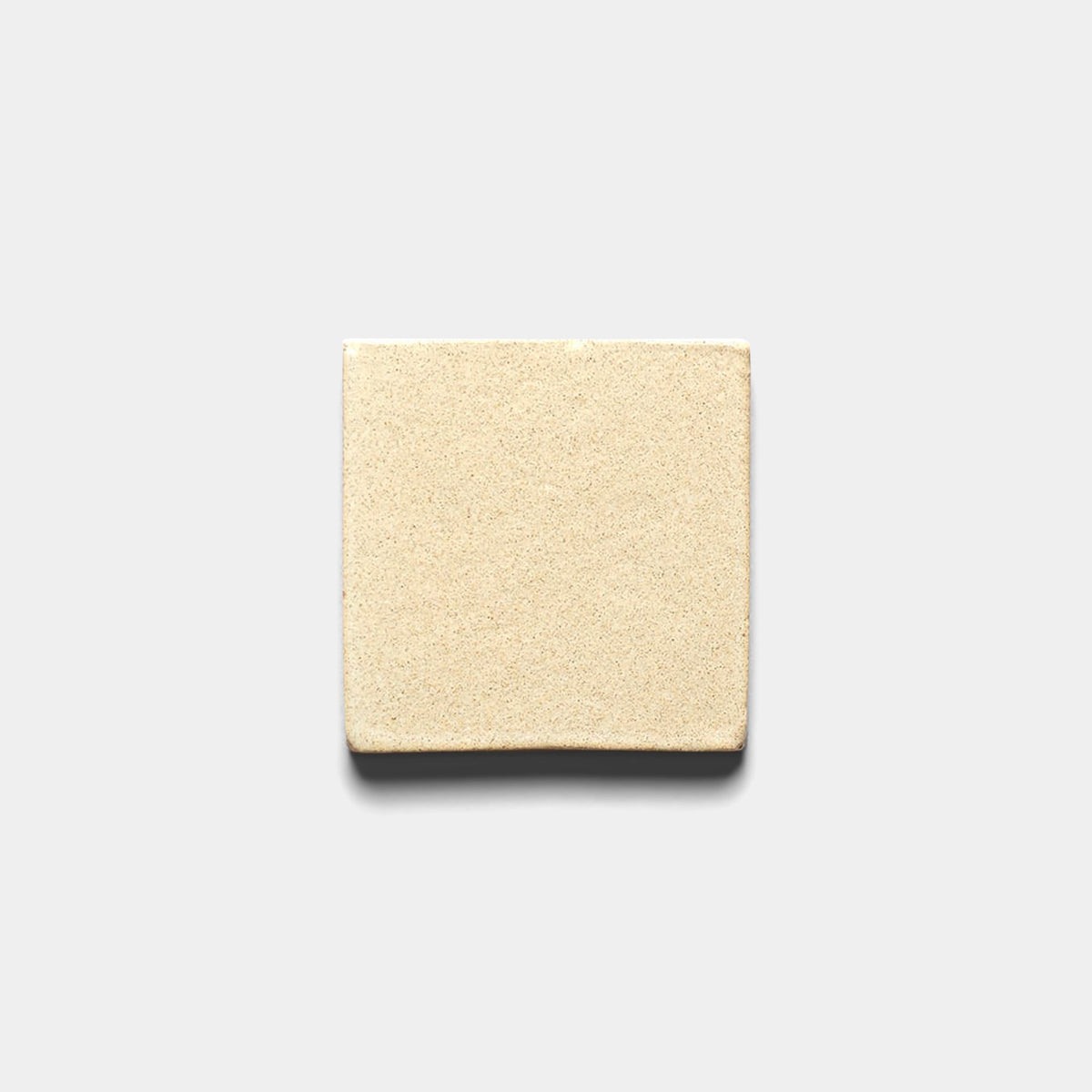 A rectangular block of beige-colored fresh yeast sits centered on a plain, light gray background, mimicking the smooth, subtly textured surface of Zia Tile’s Baja 4x4 Square sample.