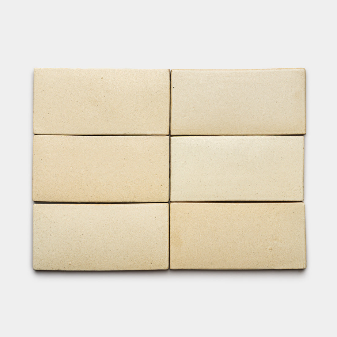 Six Baja 4x8 Rectangle tiles by Zia Tile in light beige are arranged in two rows of three on a white background, showcasing their smooth matte finish and subtle color and texture variations.