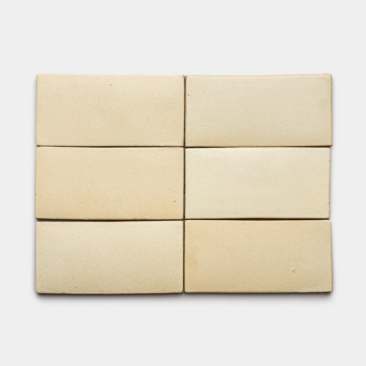 Six Baja 4x8 Rectangle tiles by Zia Tile in light beige are arranged in two rows of three on a white background, showcasing their smooth matte finish and subtle color and texture variations.