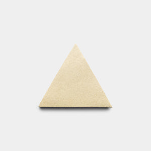 The Zia Tile Baja Triangle, a smooth and matte beige tile, is centered on a light gray background. The triangular tile has no visible markings or texture.