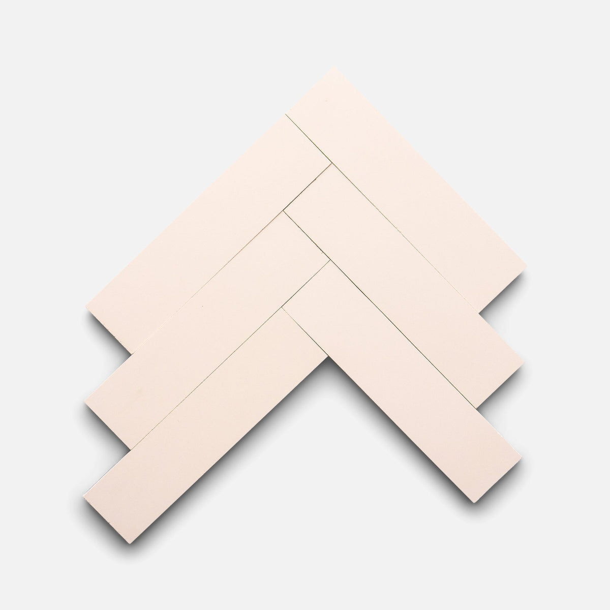 Five Ballet Slipper 2x8 tiles by Zia Tile are arranged in a herringbone pattern on a light gray background, overlapping at right angles to create a V-shaped geometric design.