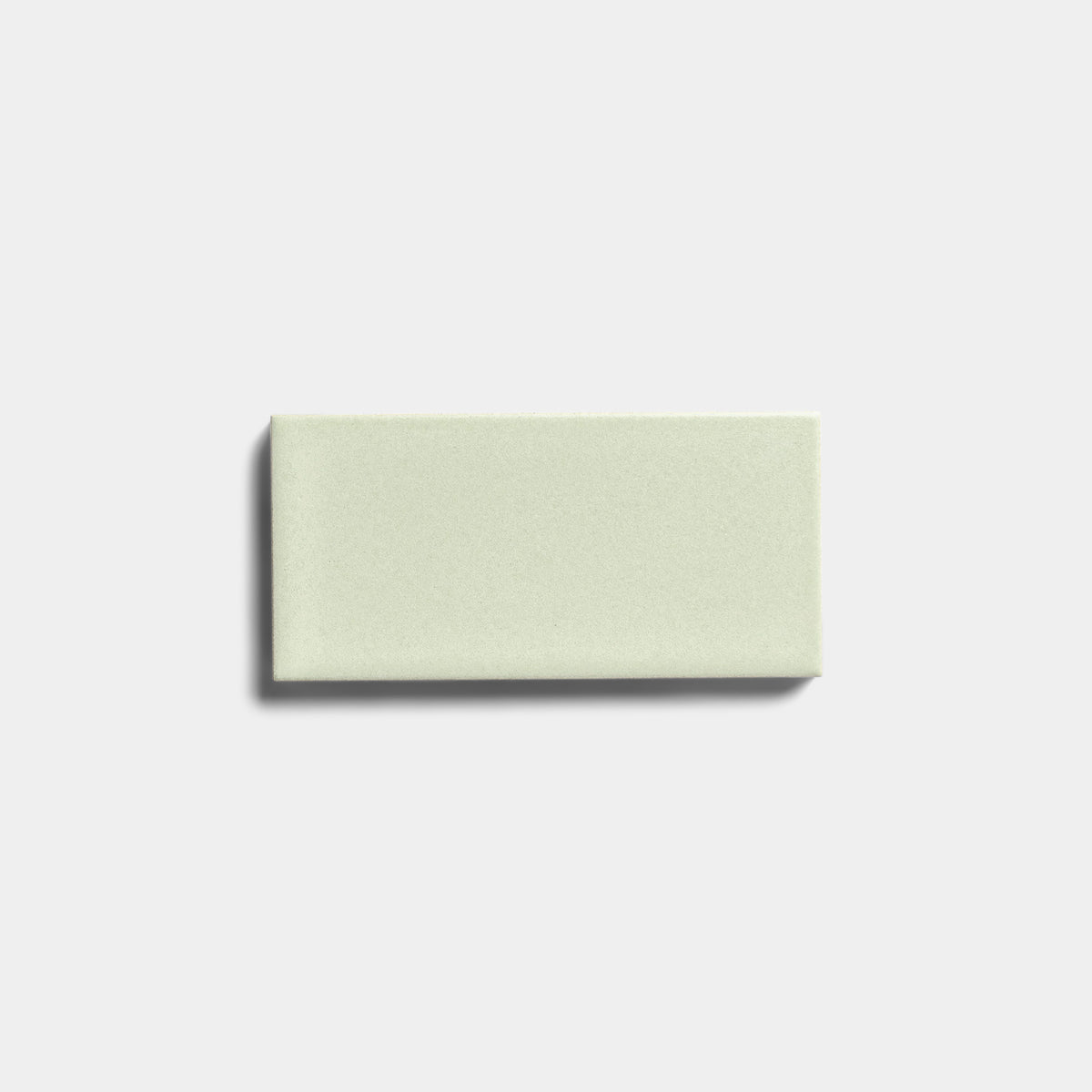 A single Balsam 2x4 ceramic tile by Zia Tile, featuring a matte finish in light green, is centered on a plain white background with a subtle shadow on its left side.