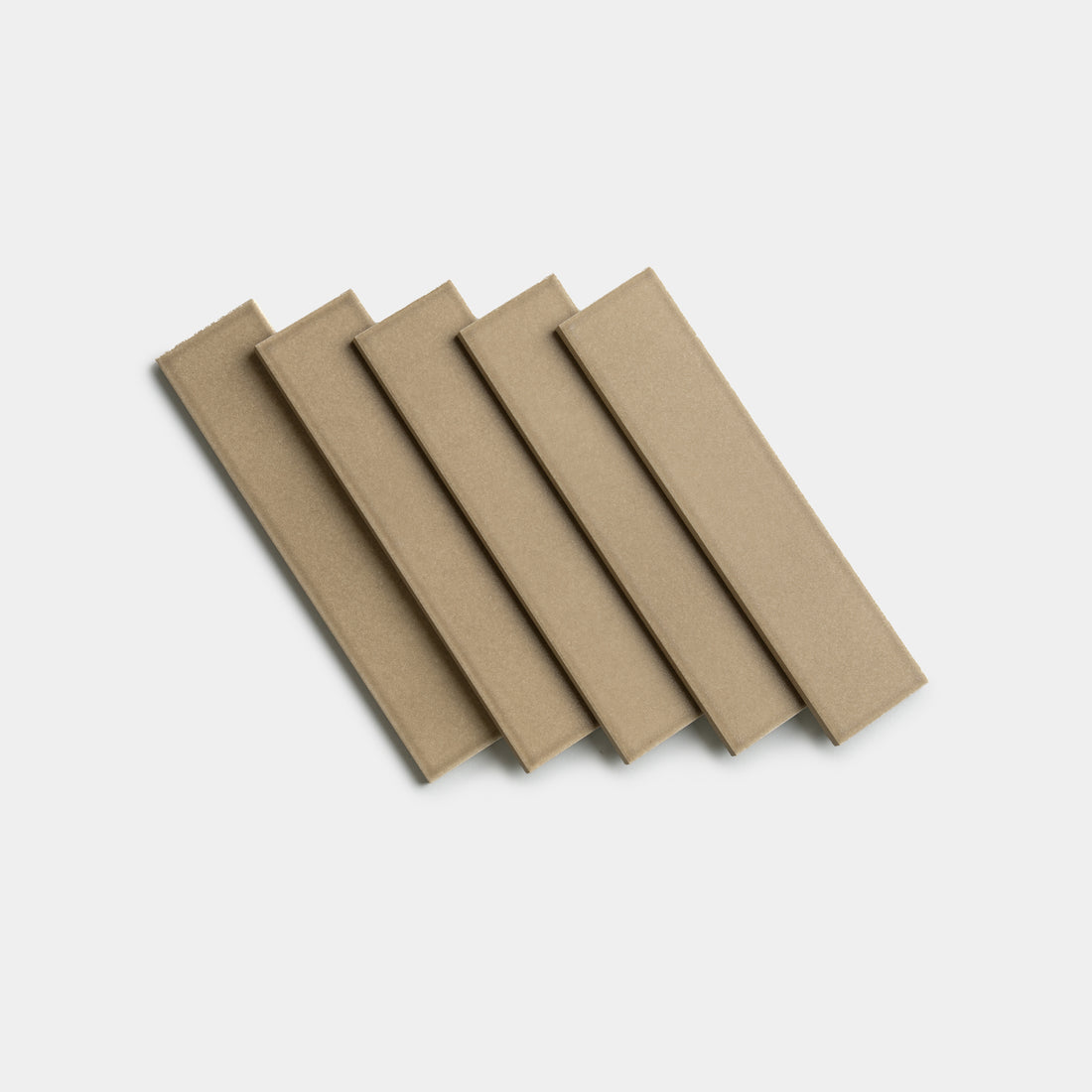 Five Barley 2x8 tiles by Zia Tile, rectangular and light brown, are arranged in a neat, slightly overlapping diagonal row on a plain white background.