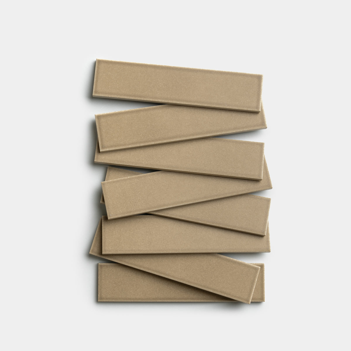 Seven Barley 2x8 tiles by Zia Tile, rectangular and beige, are arranged in an offset zigzag pattern against a white background.