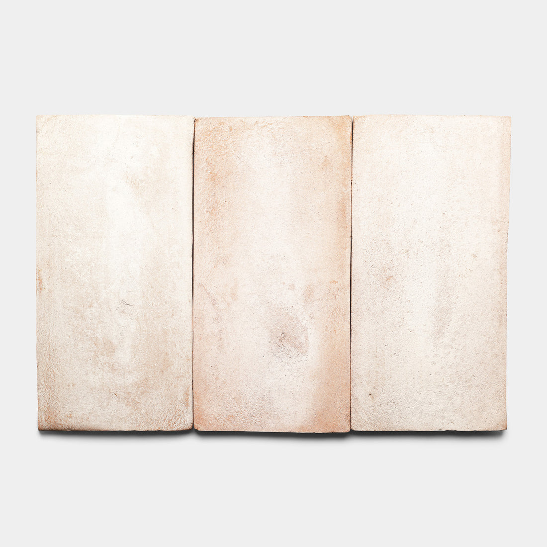 Three rectangular, light beige clay tiles with subtle texture and slight variations in color are arranged side by side against a plain white background.
