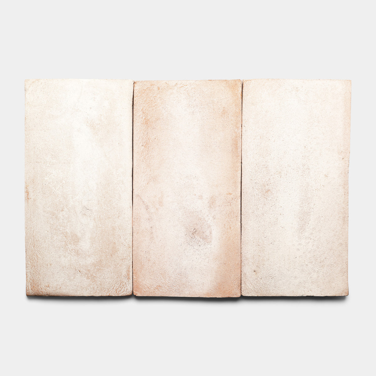 Three rectangular, light beige clay tiles with subtle texture and slight variations in color are arranged side by side against a plain white background.