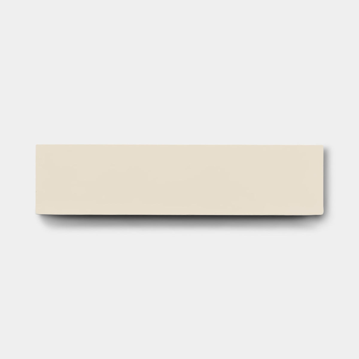 A rectangular, off-white Bone 2x8 tile sample by vendor-unknown lies centered on a plain light gray background, casting a faint shadow below and to the right—echoing the clean lines of handmade tiles.