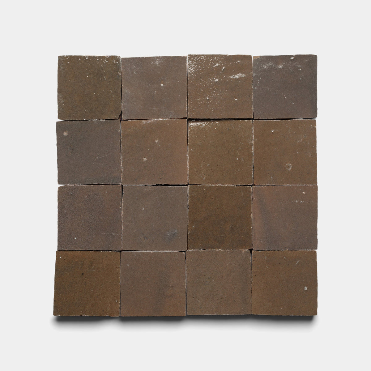 A grid of sixteen Zia Tile Brownstone 2x2 sample tiles is arranged in four rows and four columns against a light background, showing their matte finish and subtle variations in shade and texture.
