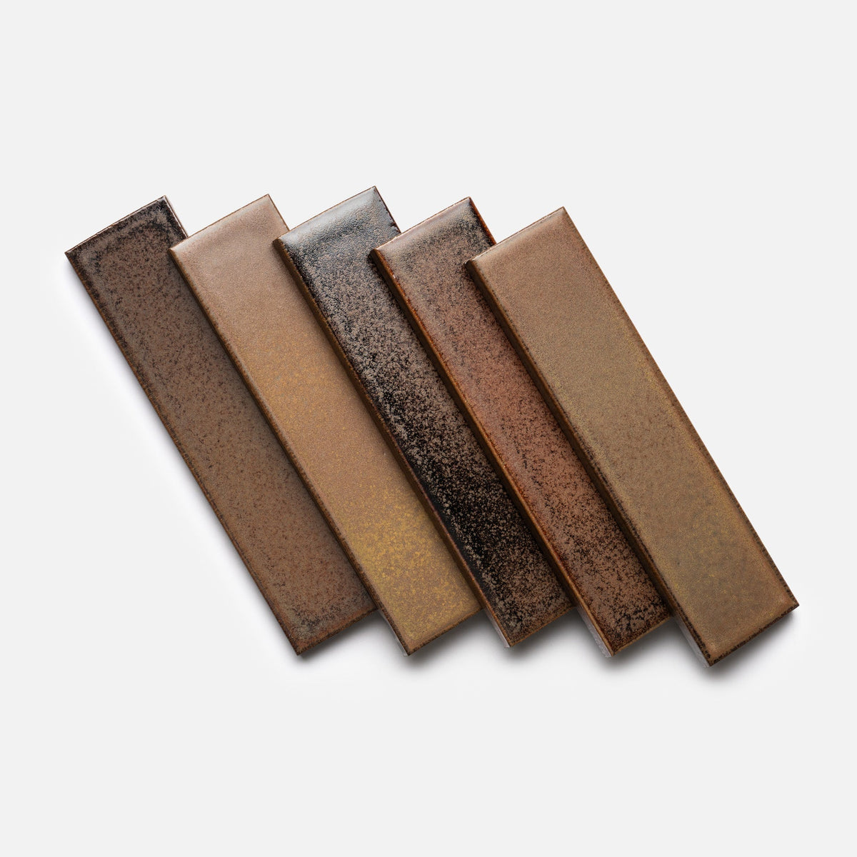 Five Buckeye + Flat ceramic tile samples by Zia Tile, in various brown shades with a textured, speckled finish, are arranged in a slightly overlapping, fanned-out display on a white background.