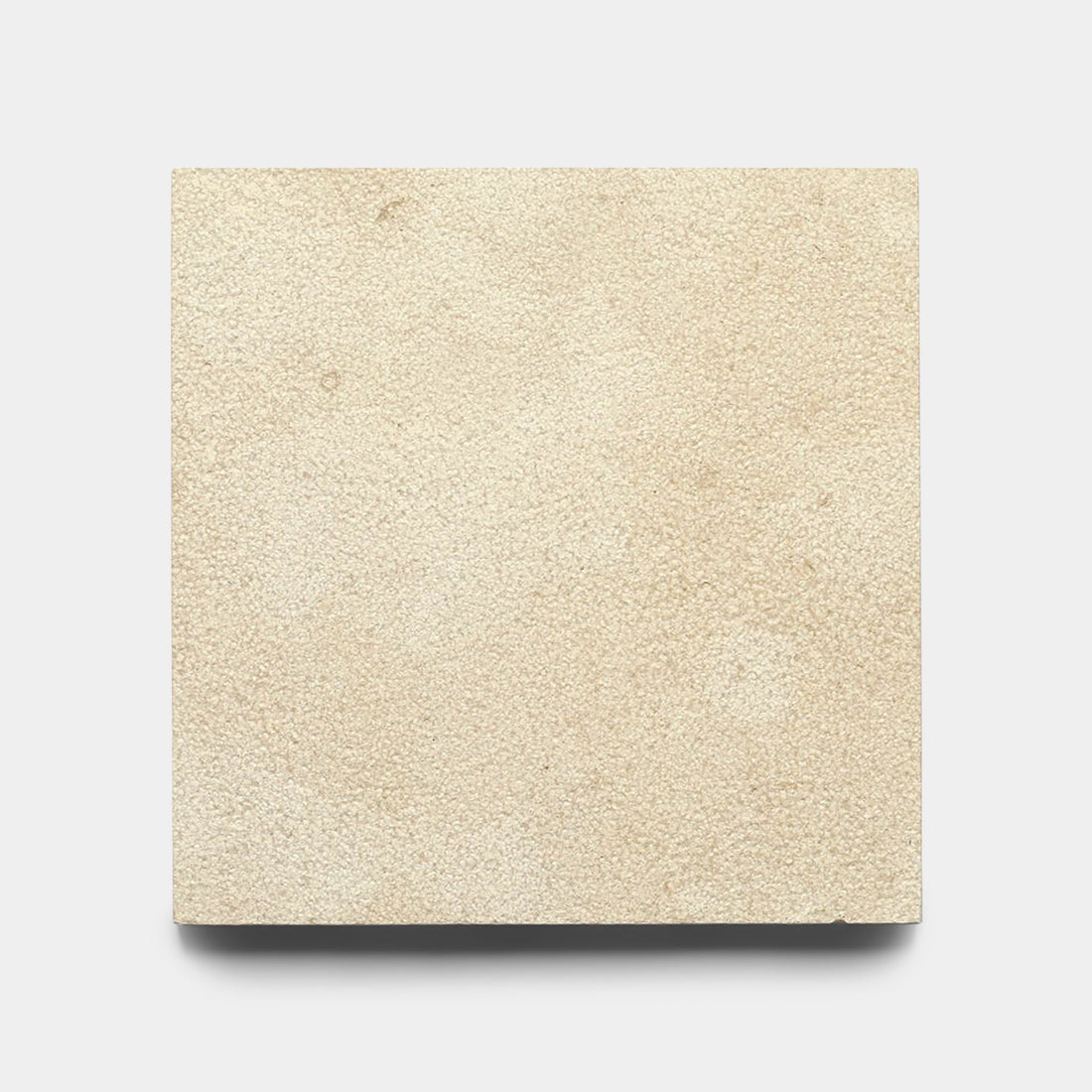A Buff 12x12 Bush Hammered Moroccan Limestone tile sample by Zia Tile, square and beige with a slightly textured matte finish, shown against a plain white background.