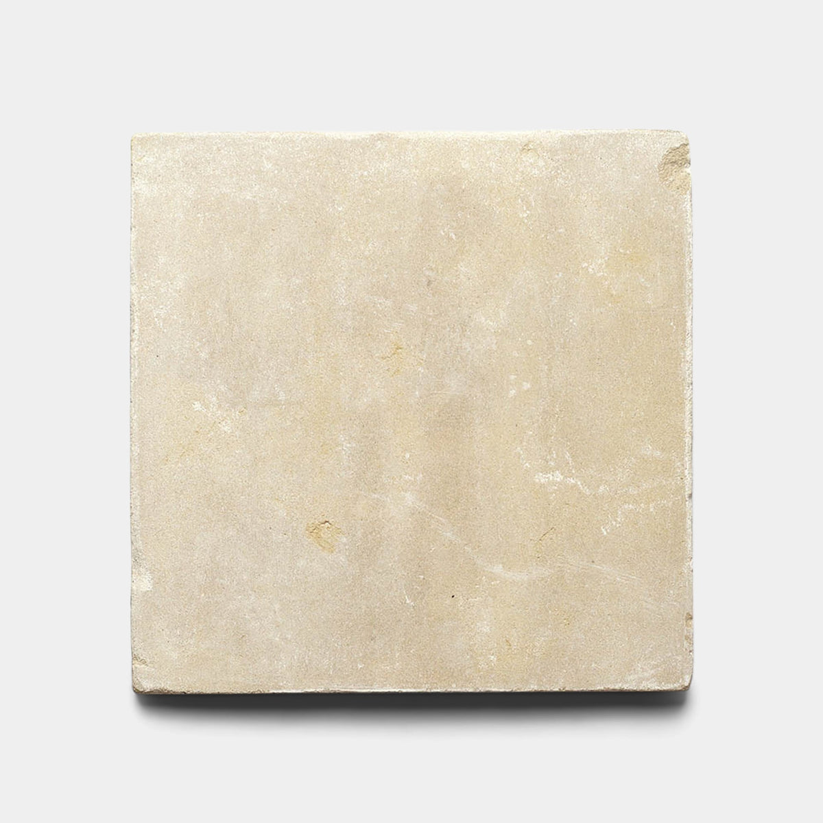 The Buff 12x12 + Honed sample by Zia Tile is a square, beige Moroccan limestone tile with a smooth honed finish and natural markings, displayed on a plain white background.