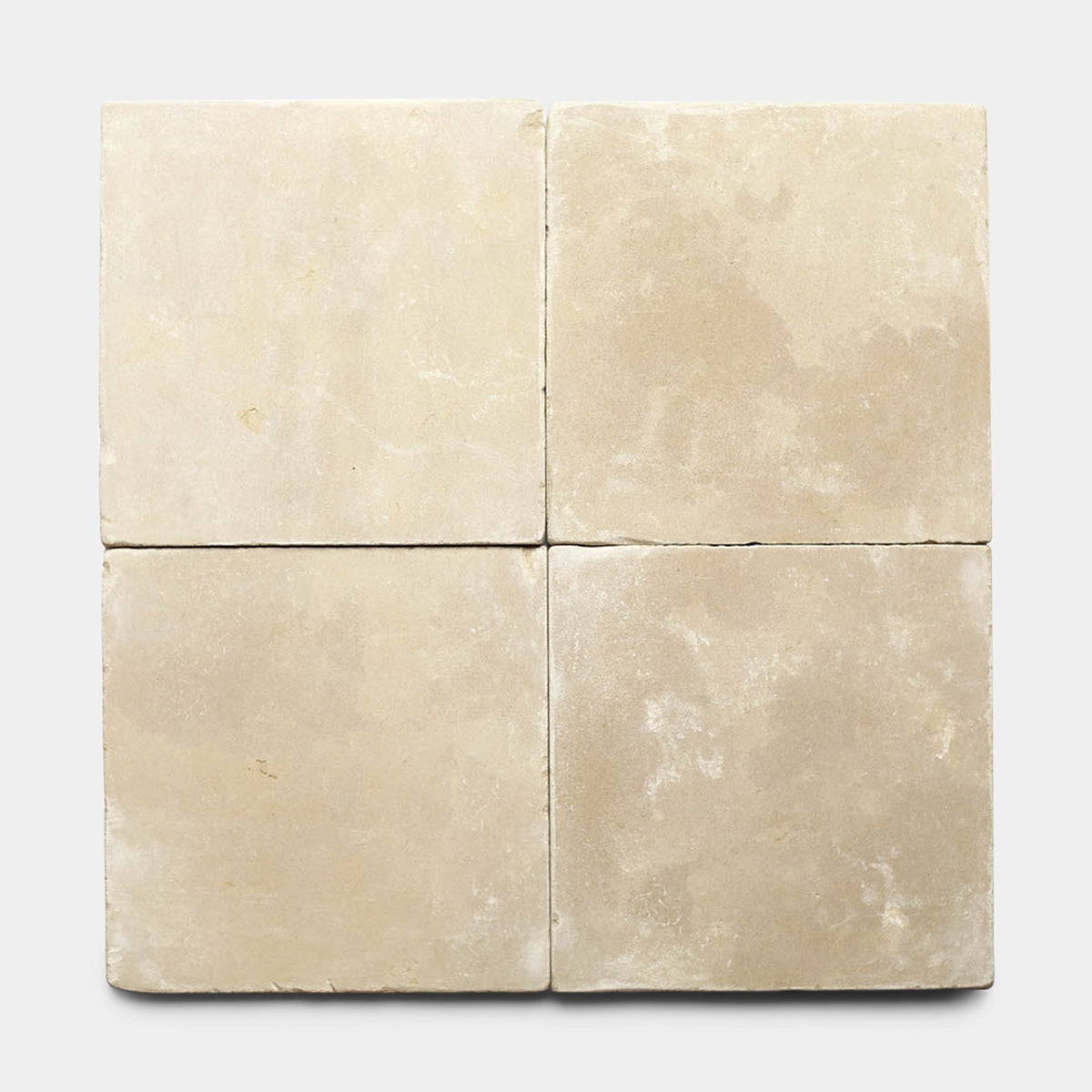 Four square, beige Buff 12x12 + Honed tiles by Zia Tile are arranged in a 2x2 grid on a light background. These Moroccan limestone samples have a slightly rough, matte finish with subtle color and texture variations.